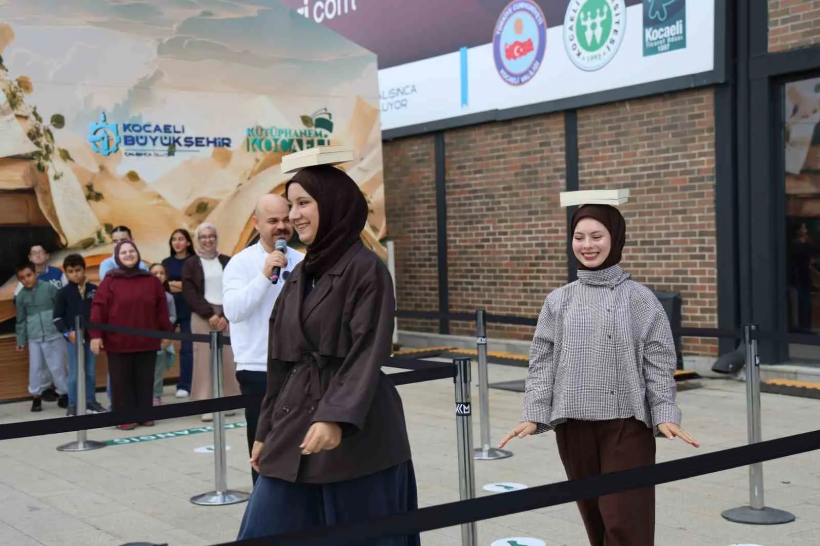 KOCAELİ KİTAP FUARI’NDA ZİYARETÇİLER, “BAŞIMIN ÜSTÜNDE YERİN VAR” OYUNUNDA KİTAPLARI BAŞLARININ ÜZERİNDE DÜŞÜRMEDEN TAŞIMAK İÇİN YARIŞTI. DENGE VE DİKKAT GEREKTİREN OYUN, FUAR ALANINDA RENKLİ VE EĞLENCELİ GÖRÜNTÜLERE SAHNE OLDU.